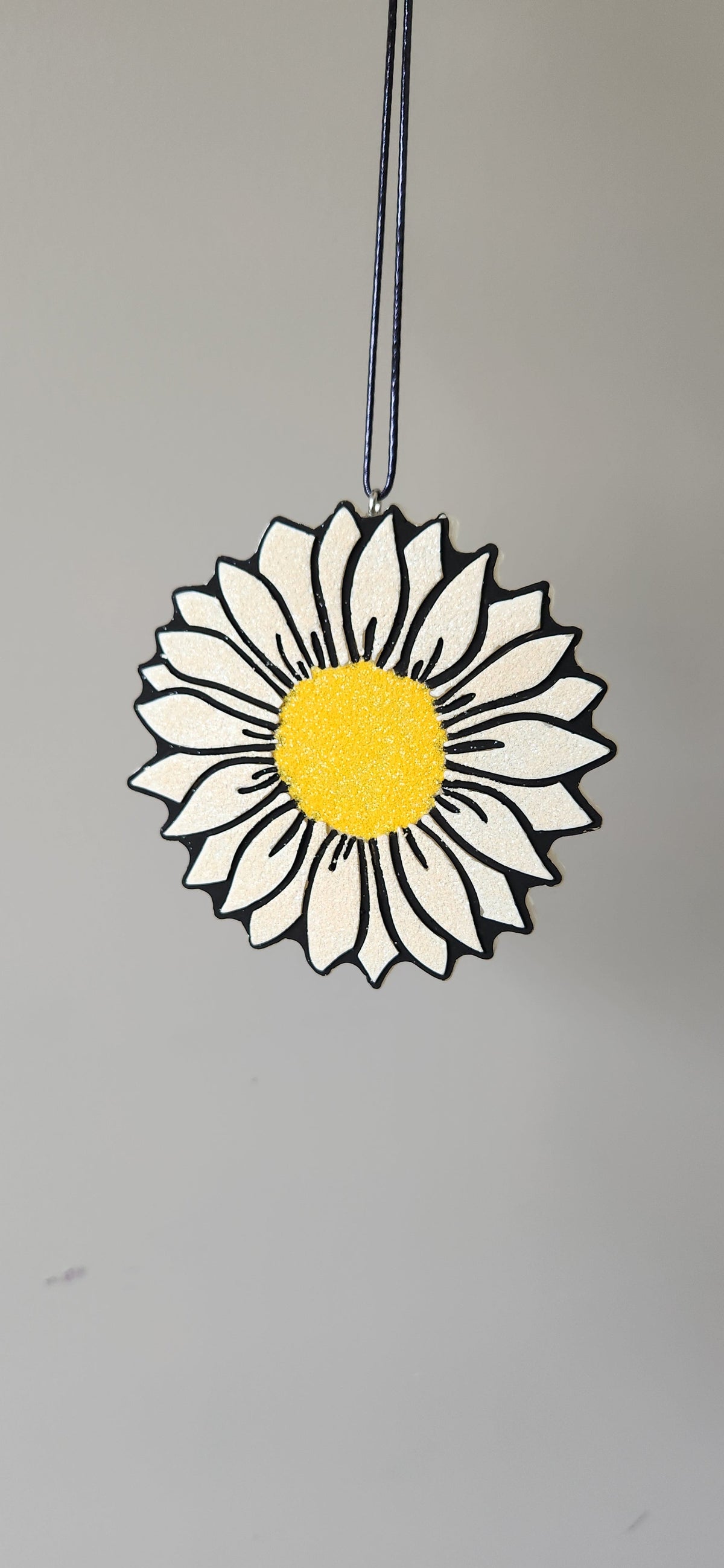 Hanging daisy flower freshener with white petals and yellow center on a string