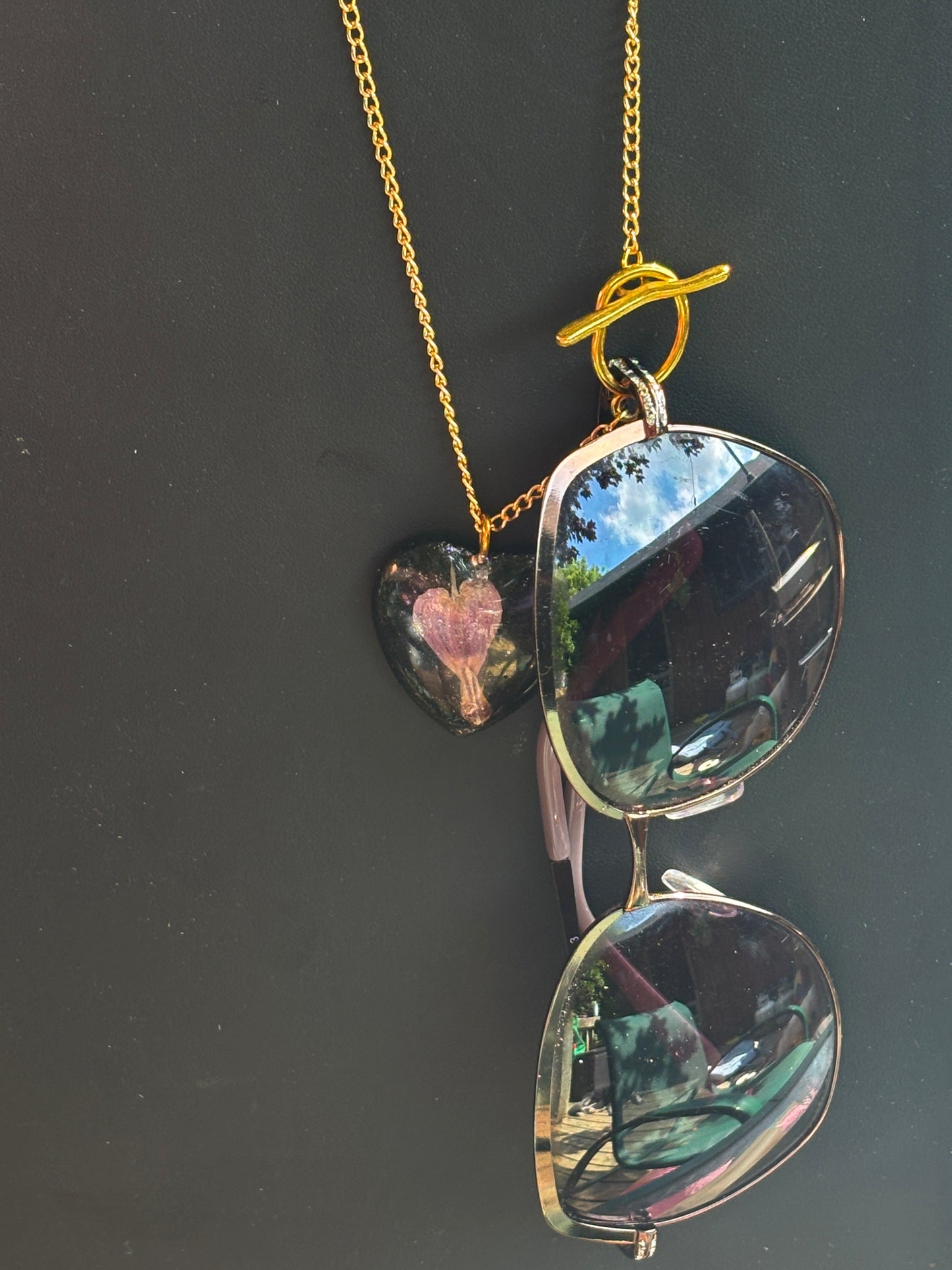 Bleeding Heart In Black Heart on Gold Sunglasses Holding Necklace