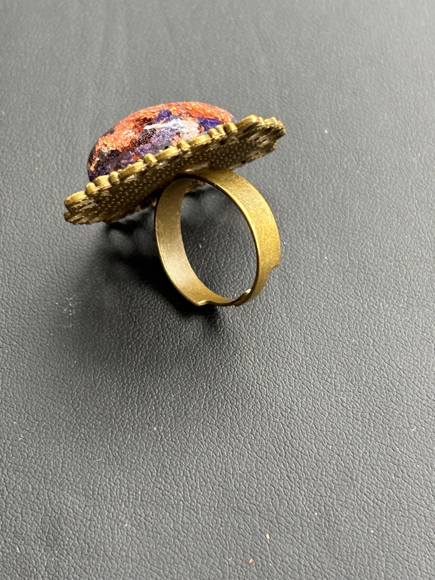 Gold-tone adjustable ring with oval cabochon top, textured band and multicolor stone