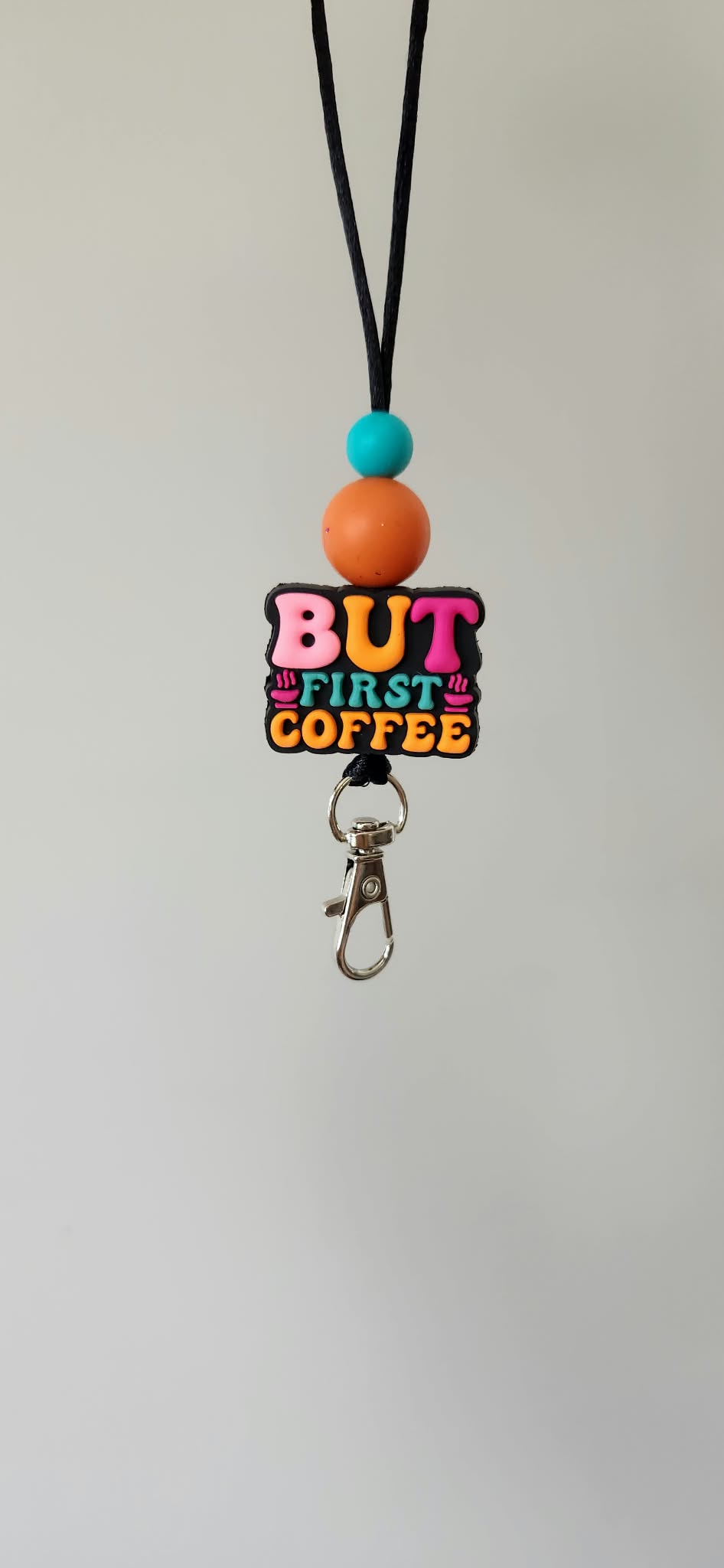 Freshie hanger with 'But First Coffee' charm, orange and teal beads on black cord, metal key clip.