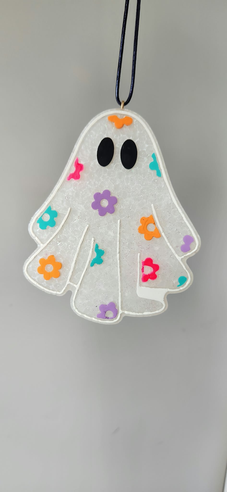 Floral ghost pendant necklace with colorful flowers and smiling face, hanging on cord
