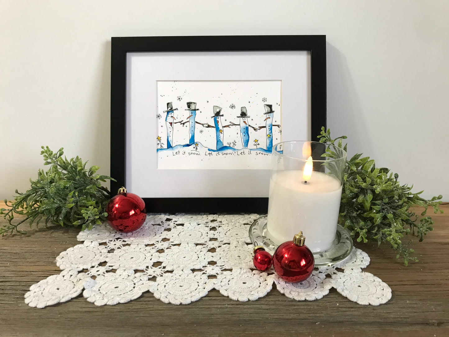 Framed winter illustration print with blue penguins and falling snow, “Let it Snow” text