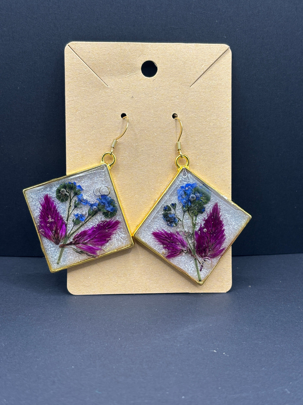 Gold floral drop earrings with square resin panels, purple celosia and blue forget-me-nots