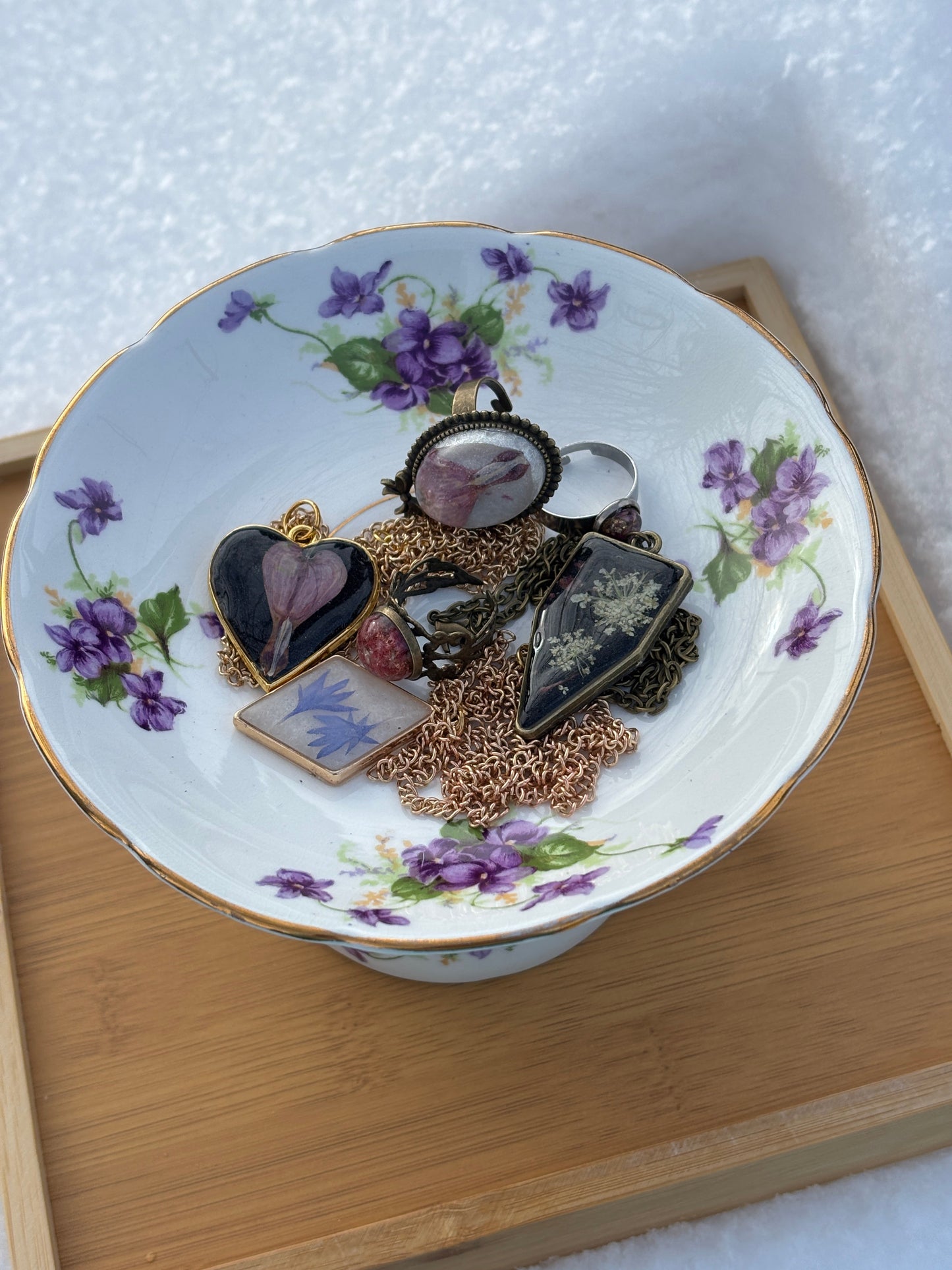 Floral tea cup jewelry holder with purple flowers, stacked heart charms on white dish