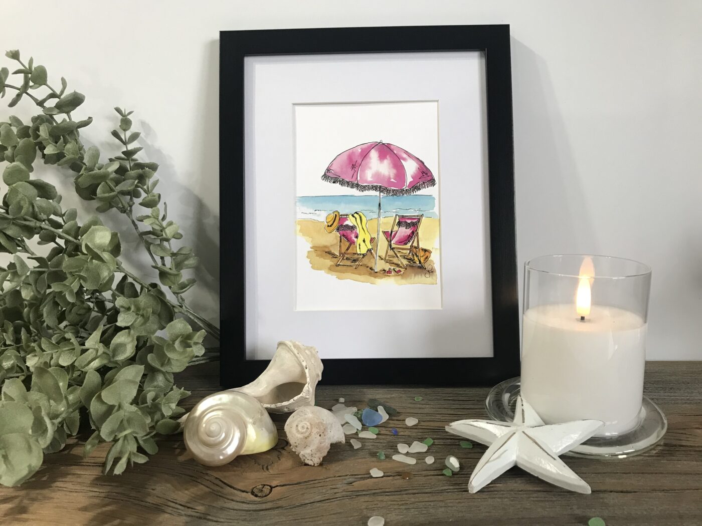 Framed beach art print with pink umbrella, chairs, sea, and sand scene