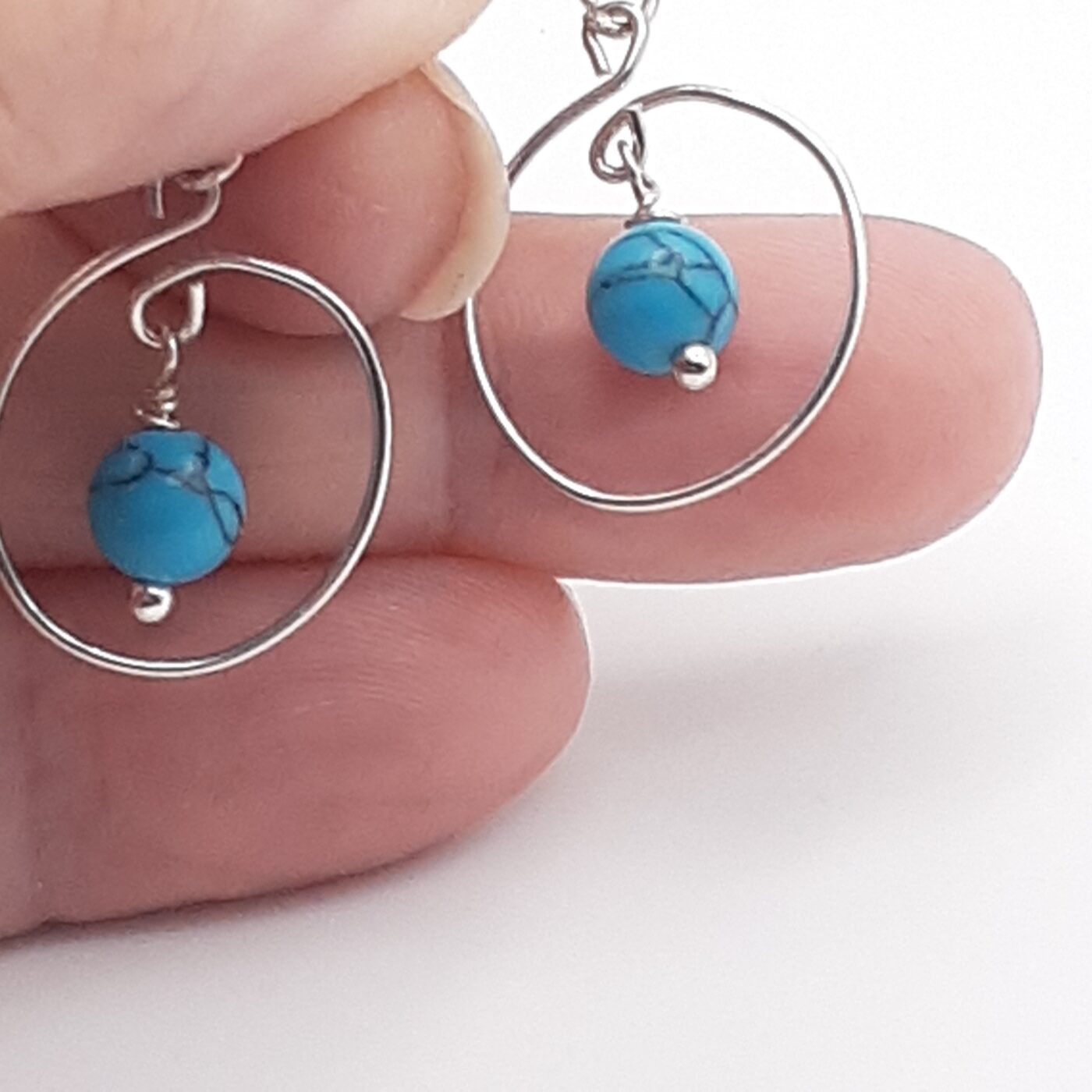 Tiny hoop post-style earrings in a swirl design with blue howlite turquoise beads