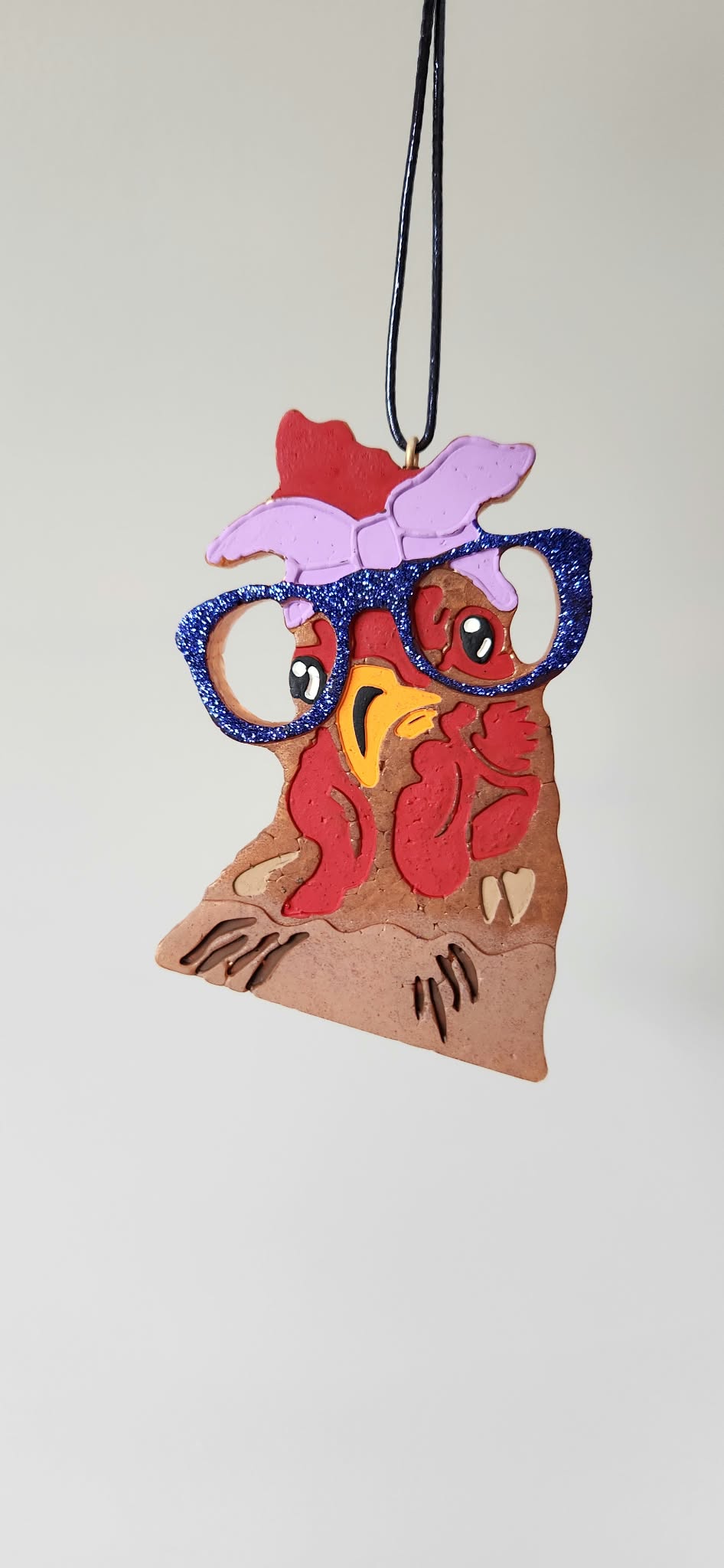 Chicken-shaped felt pendant with red body, blue outline, purple hat, on black cord