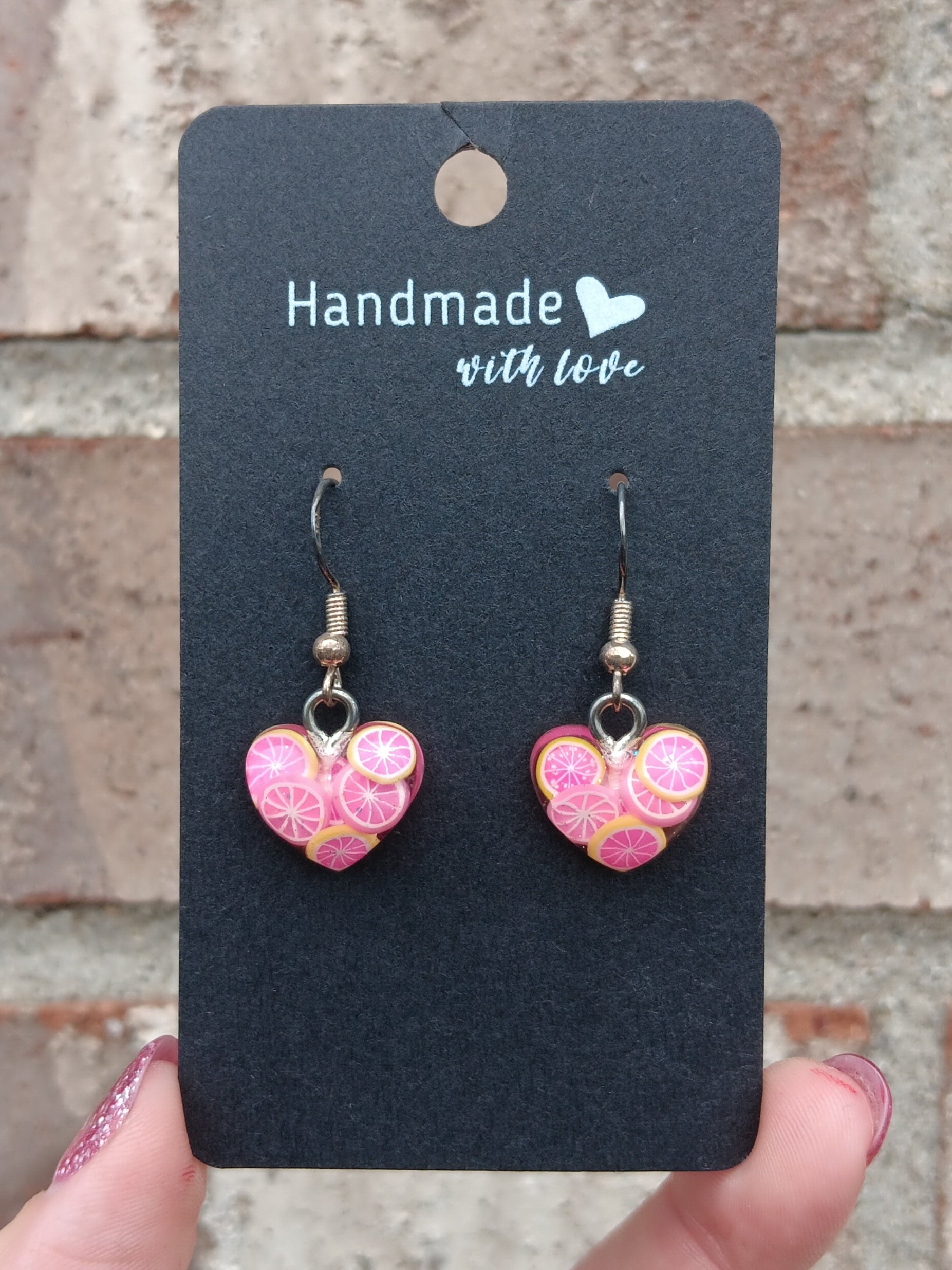 Pink heart dangle earrings with fruit slice resin charms, on card backing