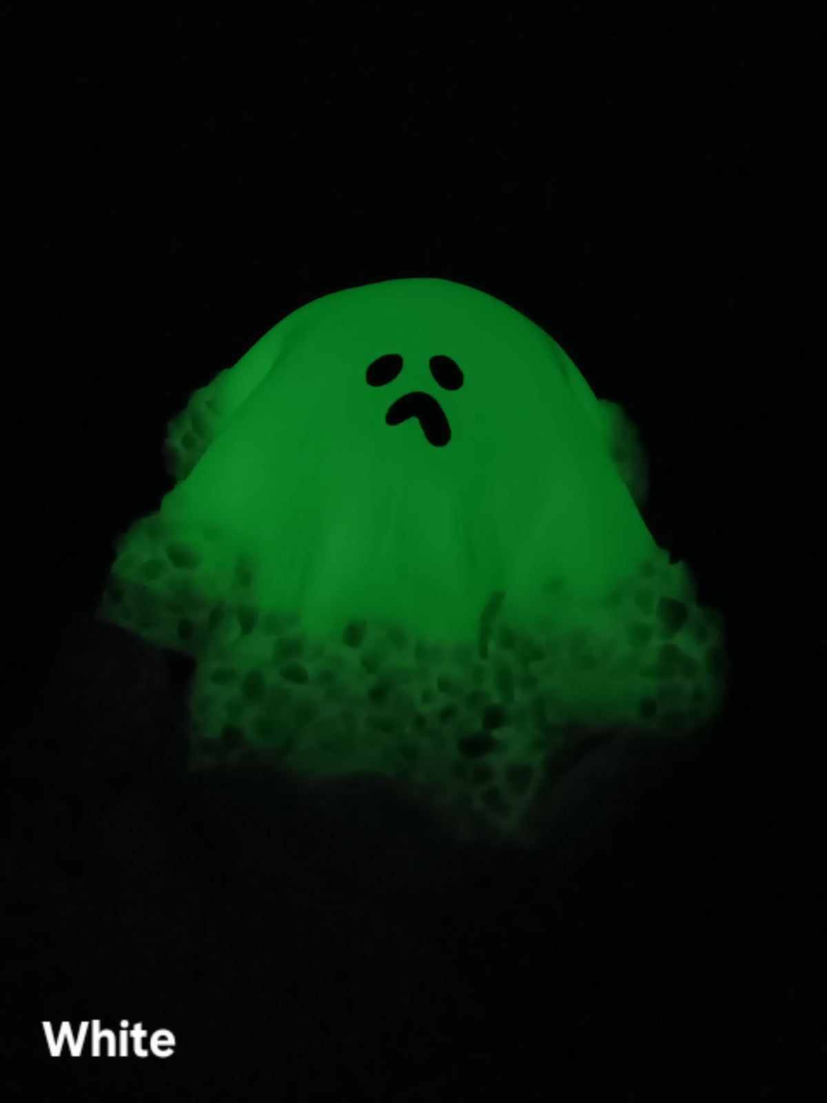 Glow-in-the-dark ghost figurine glowing green with black face, puffed hood, medium