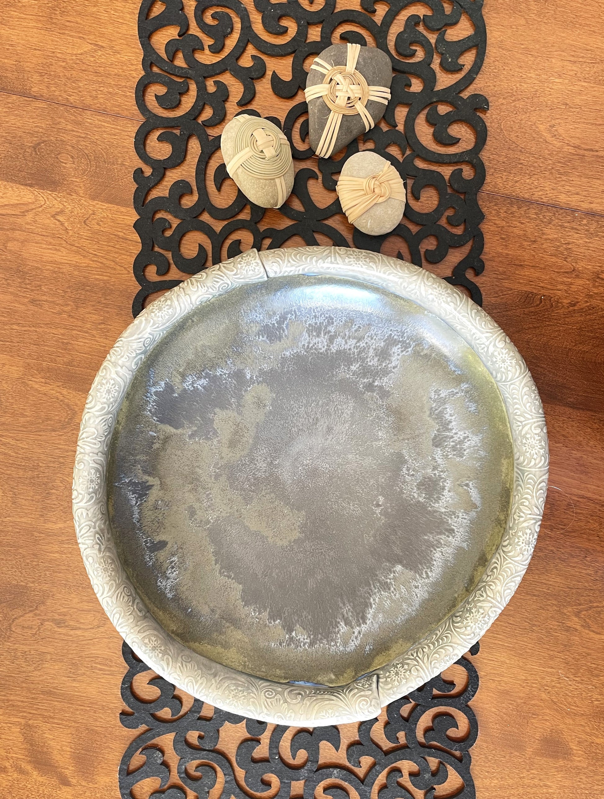 Round decorative serving bowl with embossed silver rim and gray mottled center on tabletop
