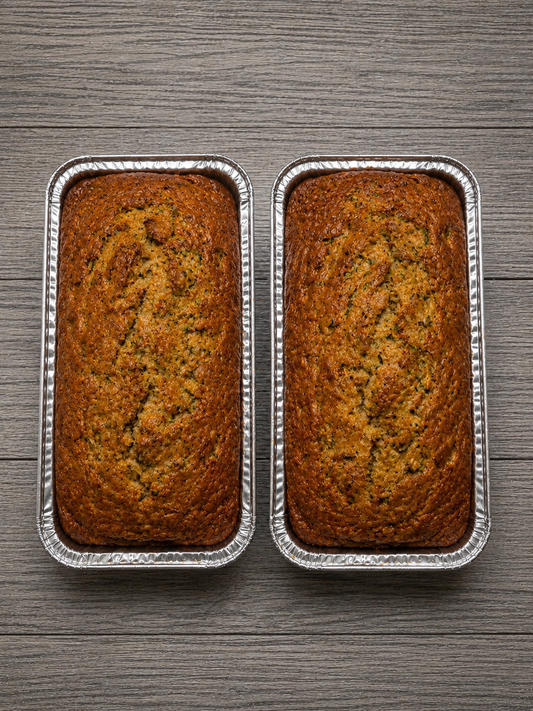 Zucchini bread loaf, golden-brown speckled crumb in foil tray, two loaves