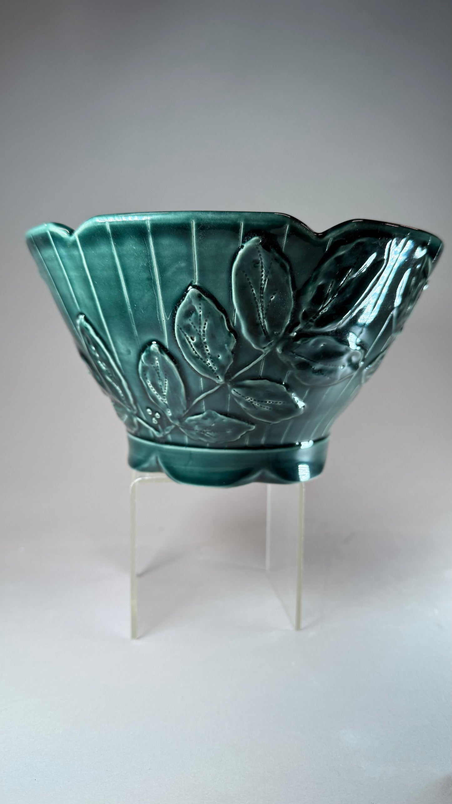 Teal green ceramic bowl with raised leaf pattern, glossy black rim and scalloped edge