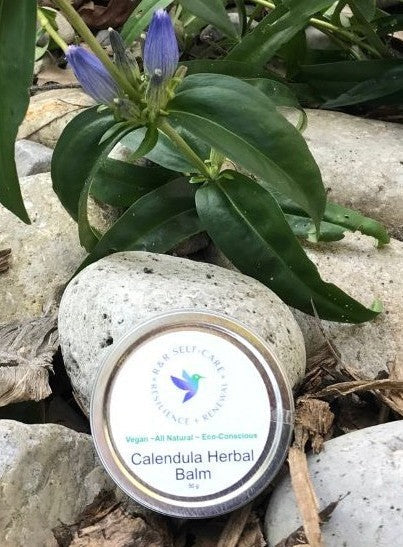 Calendula herbal balm tin with round label; vegan and essential oil text visible