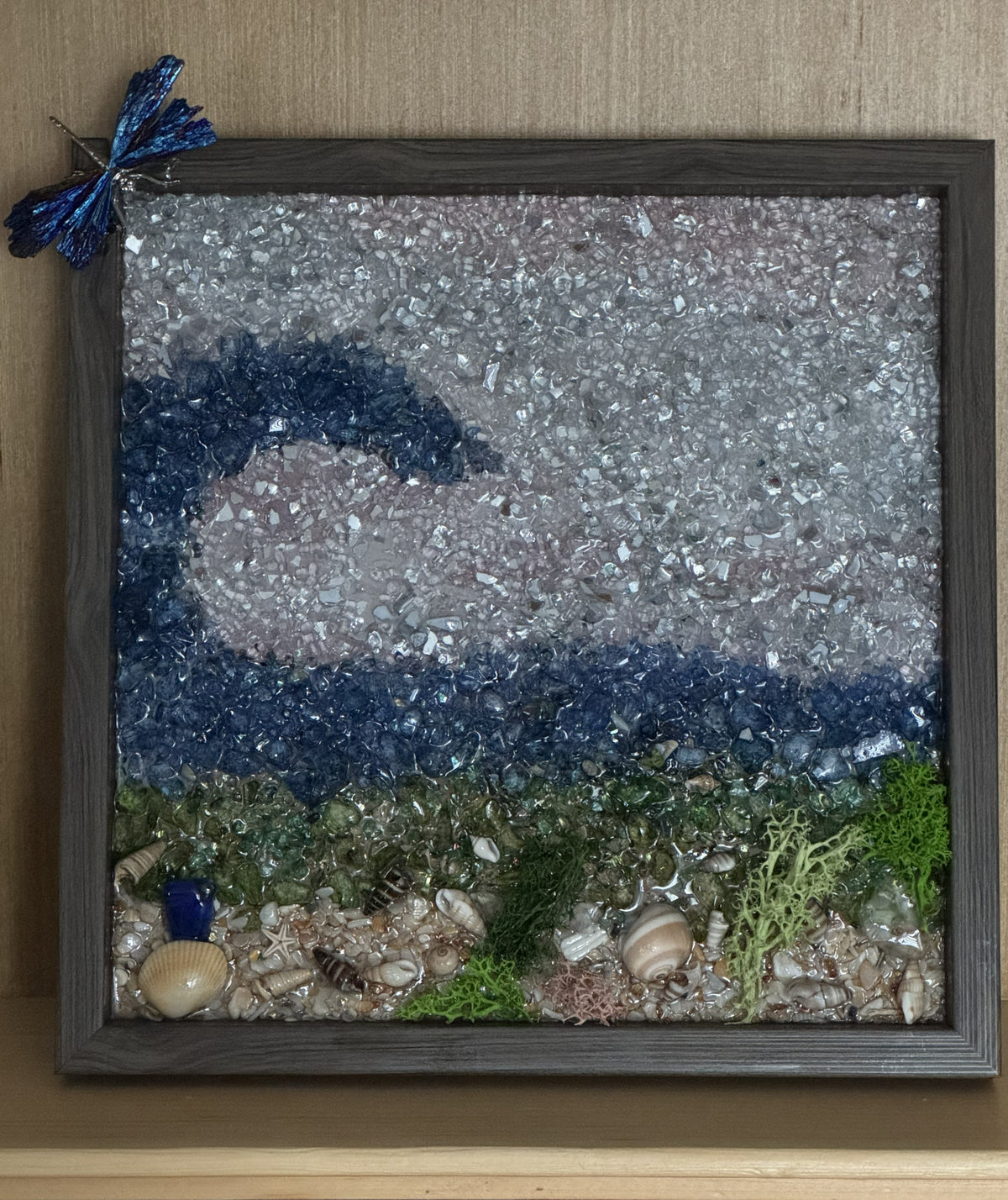Ocean wave glitter frame with shells and sea grass, dragonfly perched top left