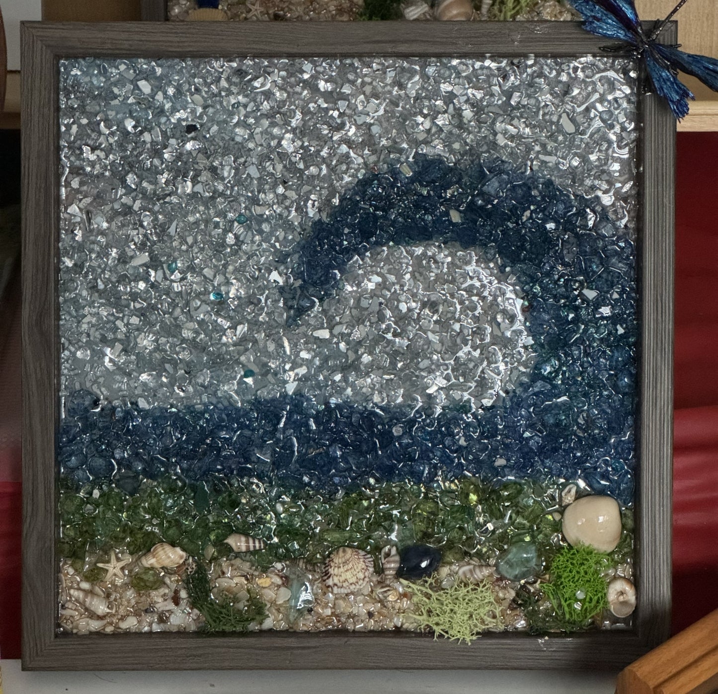 Ocean wave glitter frame with shells and sea grass, dragonfly perched top right