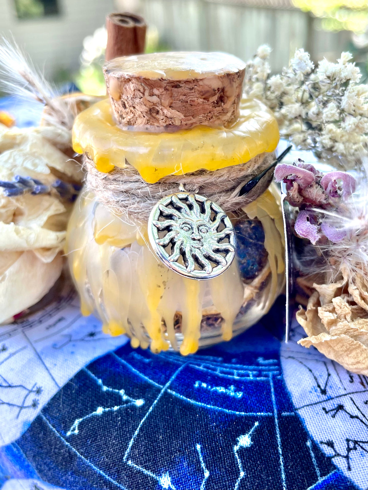Glass spell jar with yellow wax seal and silver sun-faced charm, cork top