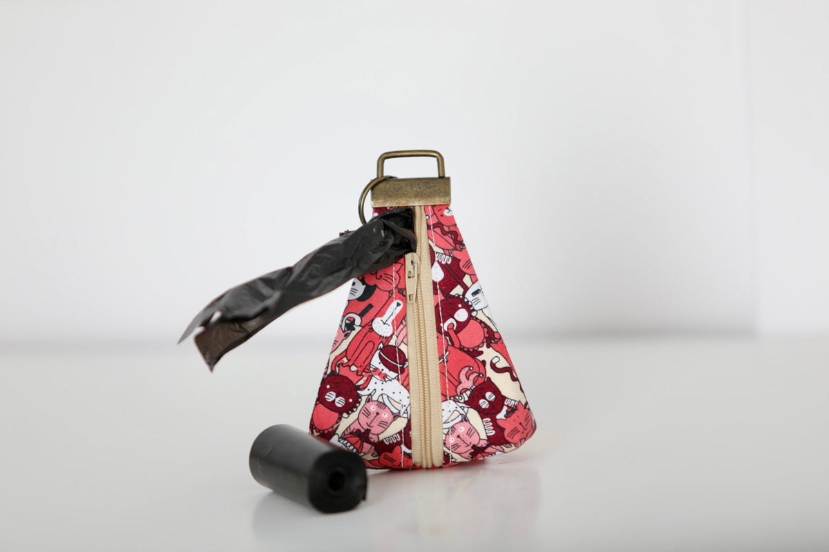 Keychain poop bag holder pouch with red patterned fabric, black roll and black bag.