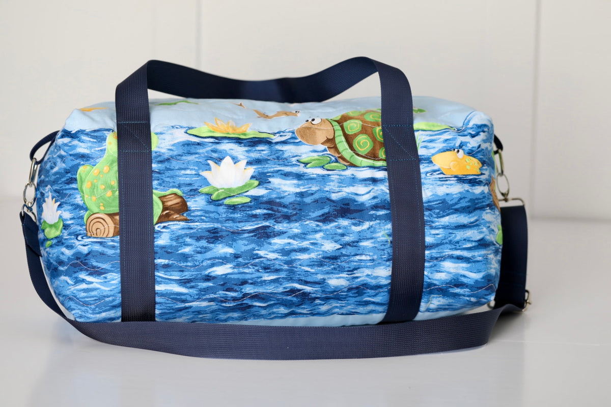 Kids duffle bag with blue ocean pond print and navy carrying straps, top zipper