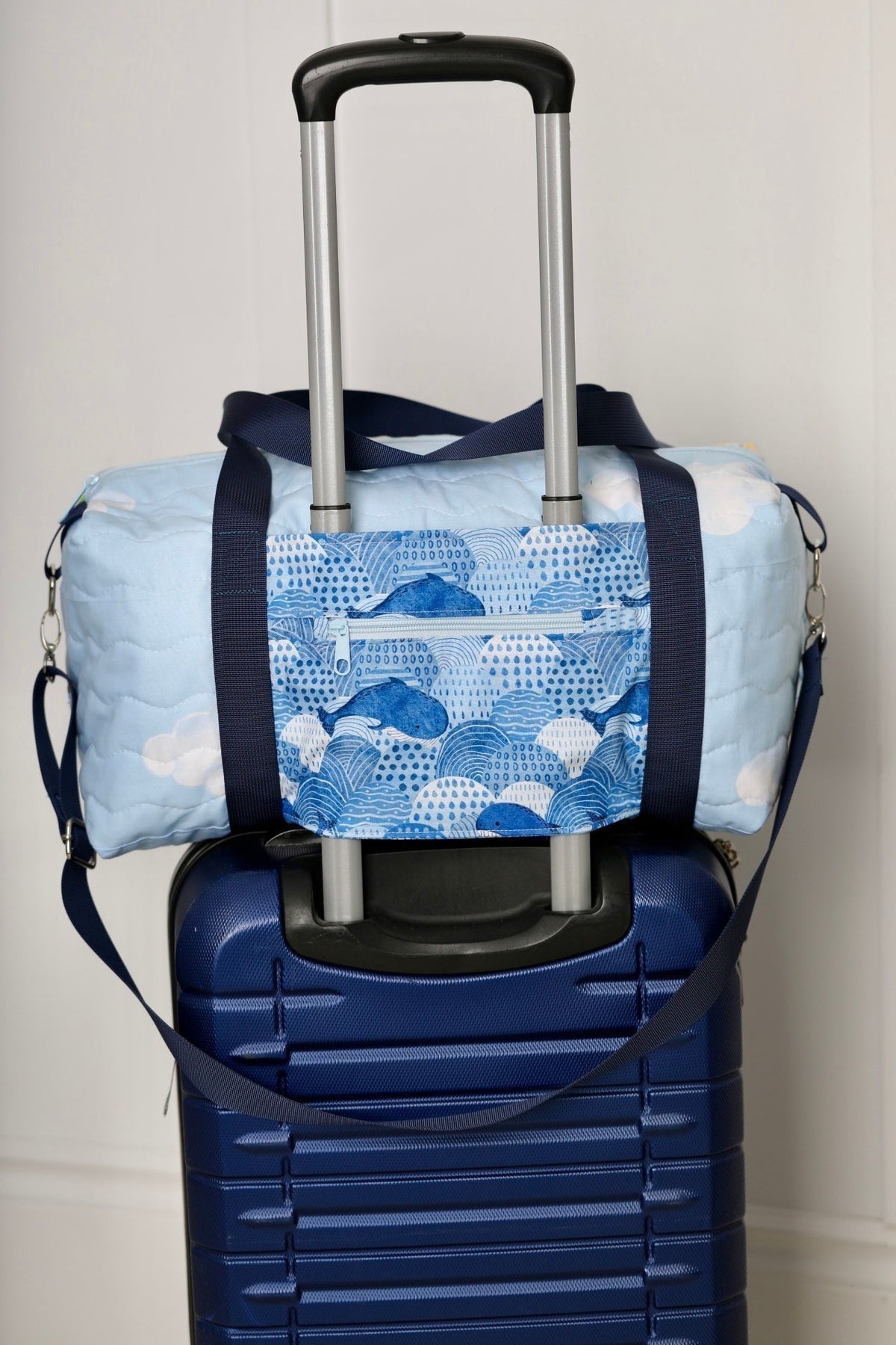 Kids duffle bag with blue ocean print and navy straps, shown with rolling handle