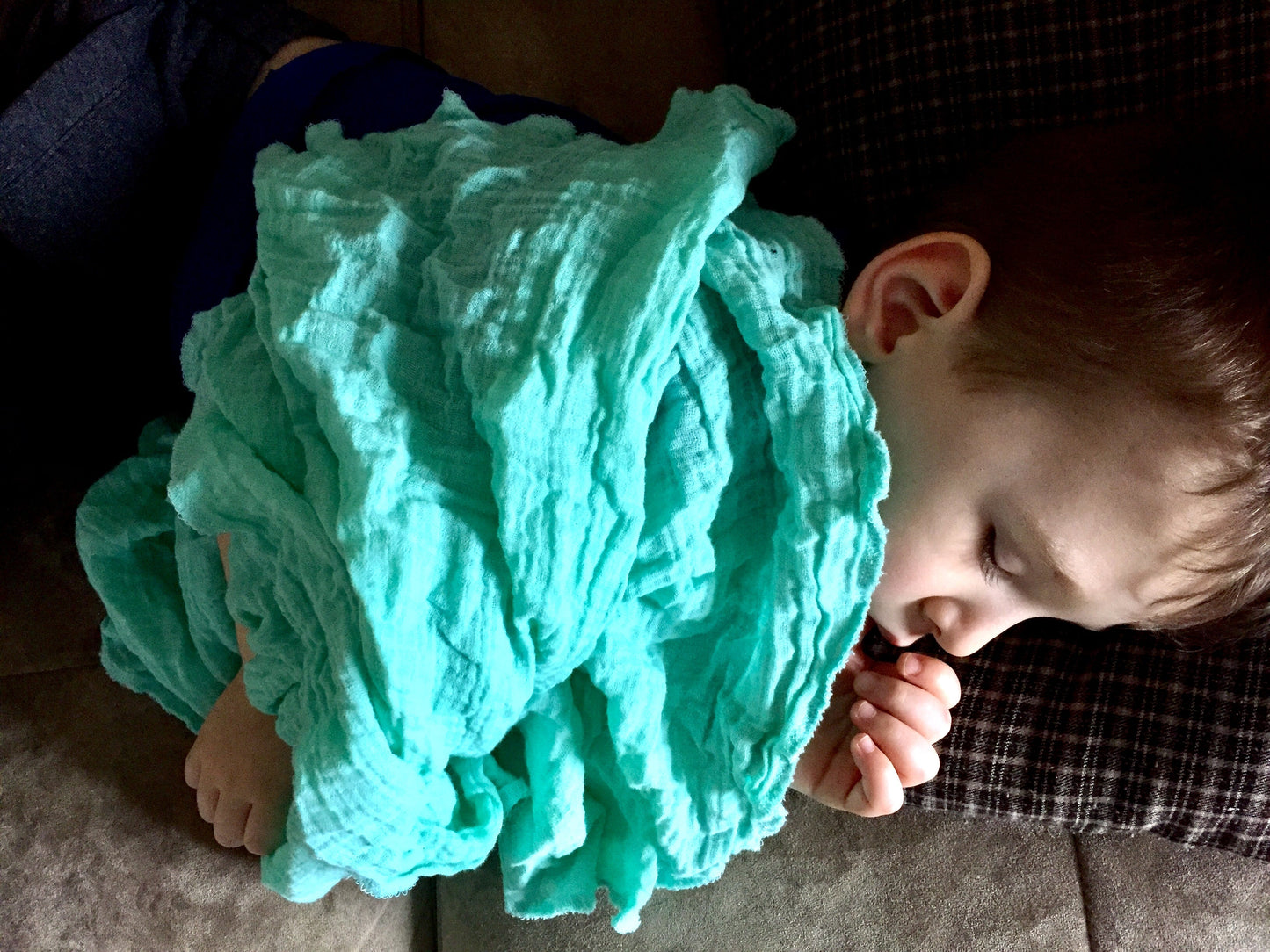 Turquoise ruffled swaddle blanket swaddling baby, hands near face