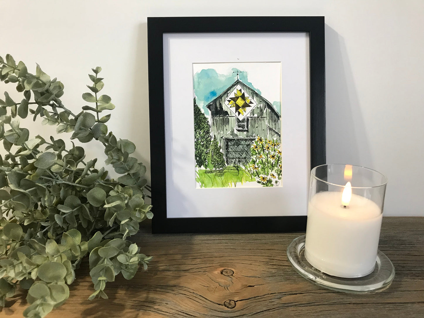 Framed quilt barn wall art print with colorful house and green landscape