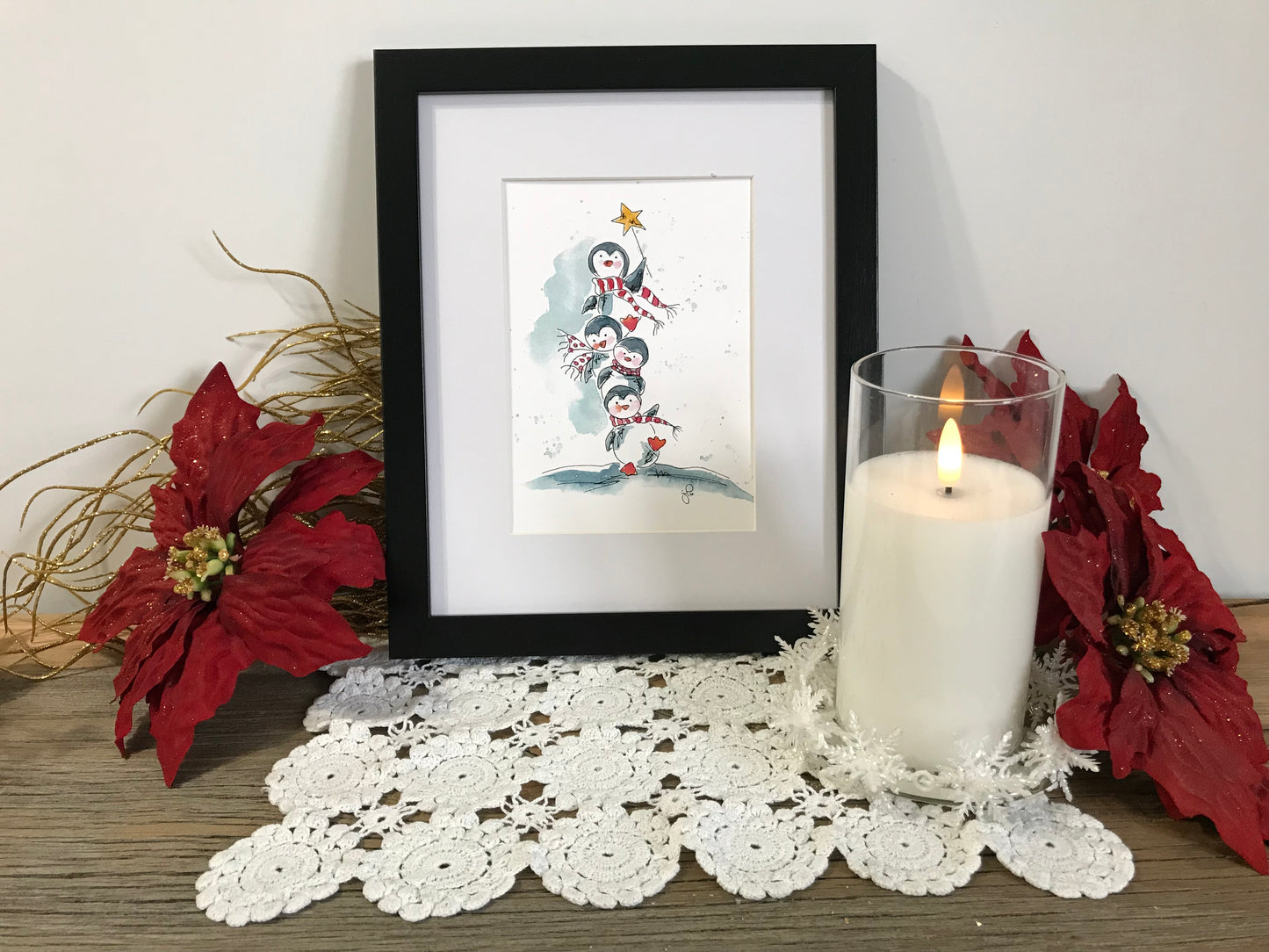 Framed penguin illustration in black frame, stacked penguins with star accents