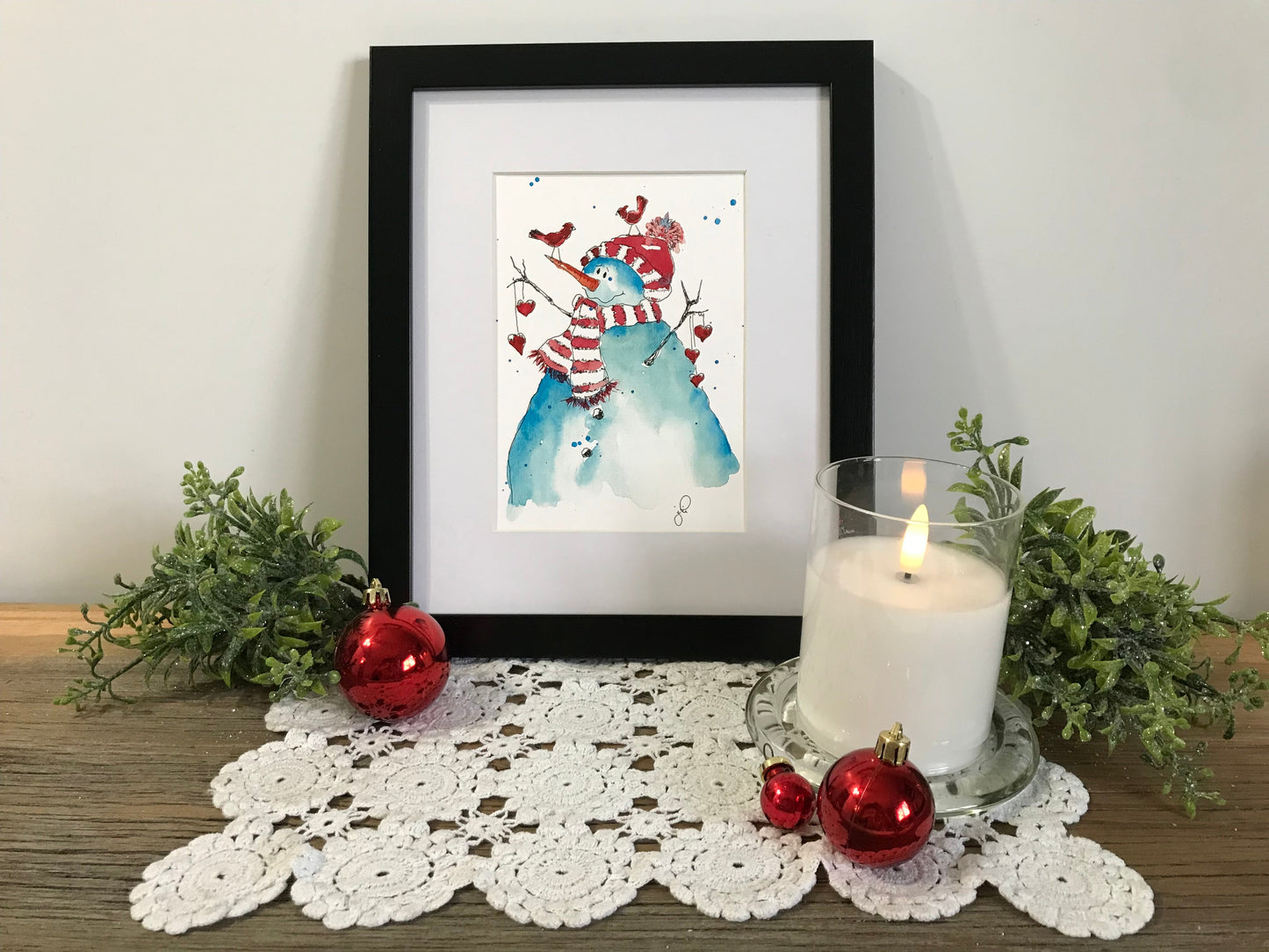 Framed snowman and friends watercolor-style wall art with red and blue figures
