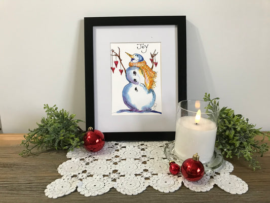 Framed holiday snowman illustration with blue scarf and hat, red accents, Joy banner