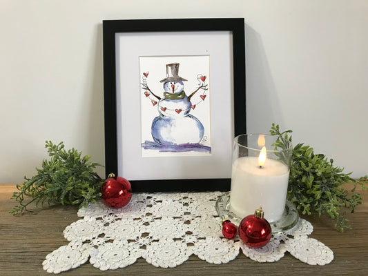 Framed snowman illustration in black frame with top hat and red details