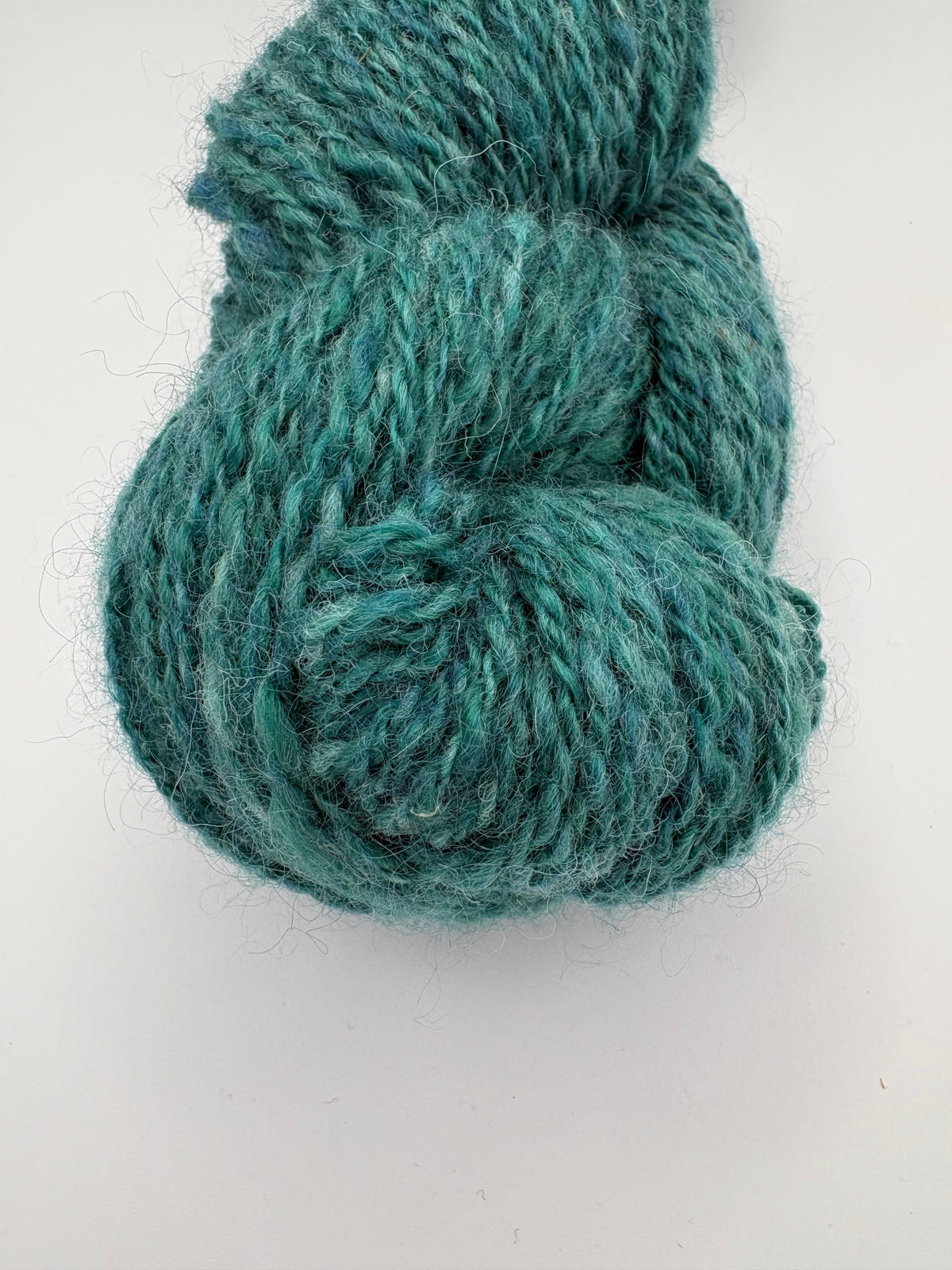 Teal handspun wool yarn skein, round twist texture close-up