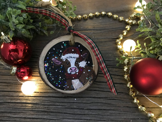 Hand-painted round wooden ornament with cow illustration and hanging ribbon