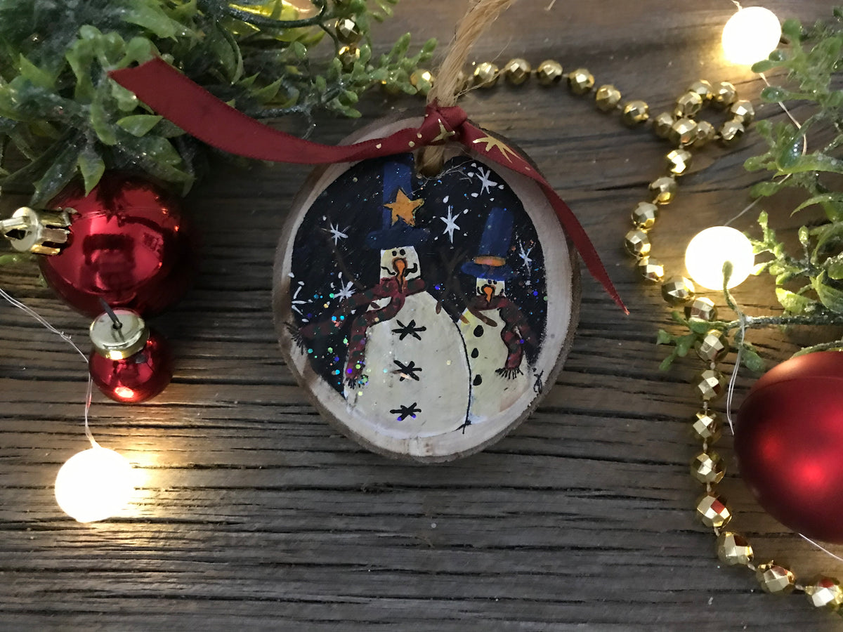 Hand-painted round wooden ornament with two snowmen figures and blue starry details