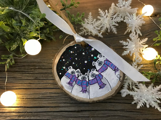 Round wooden ornament hand-painted with polar bears and stars, hanging on ribbon