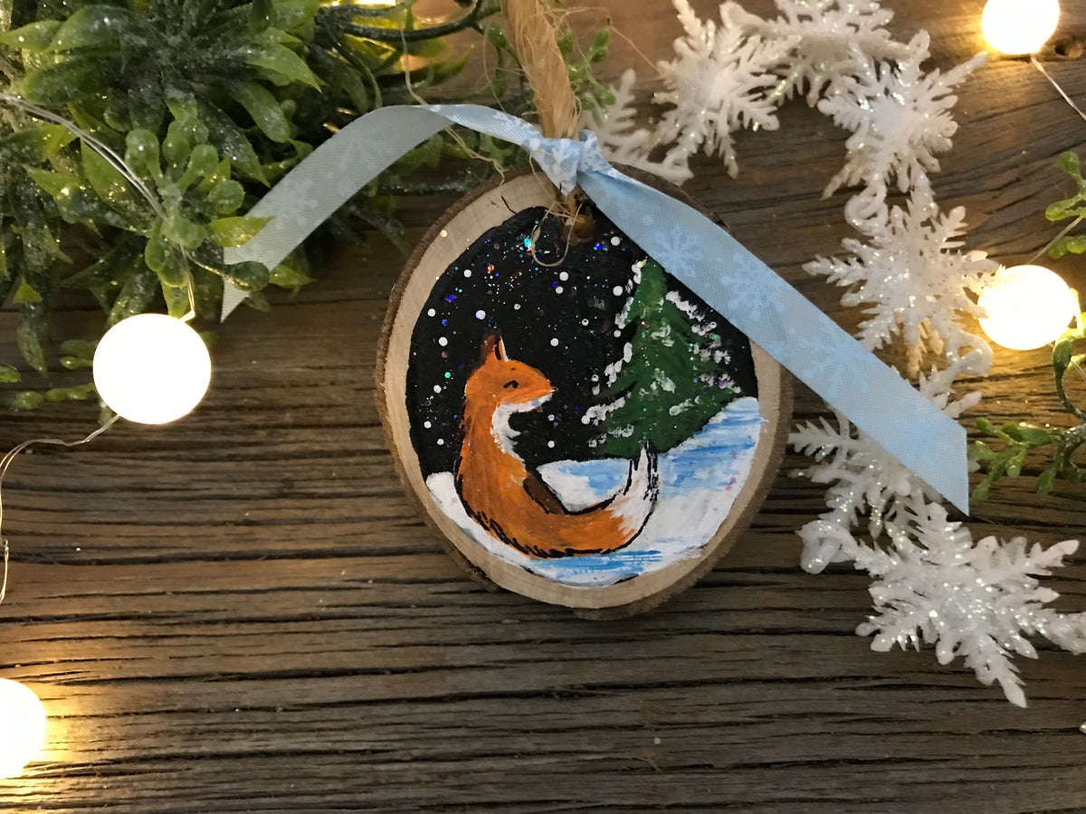 Hand-painted fox-and-tree wooden ornament with blue hanging ribbon
