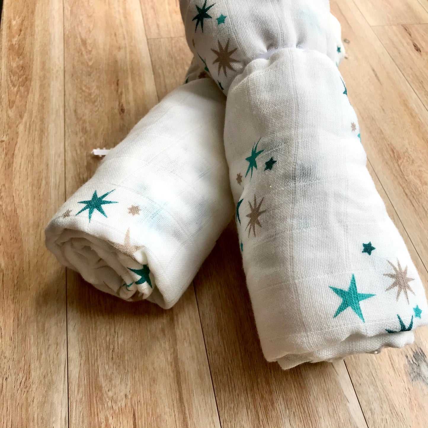 White swaddle blanket with teal and brown star pattern