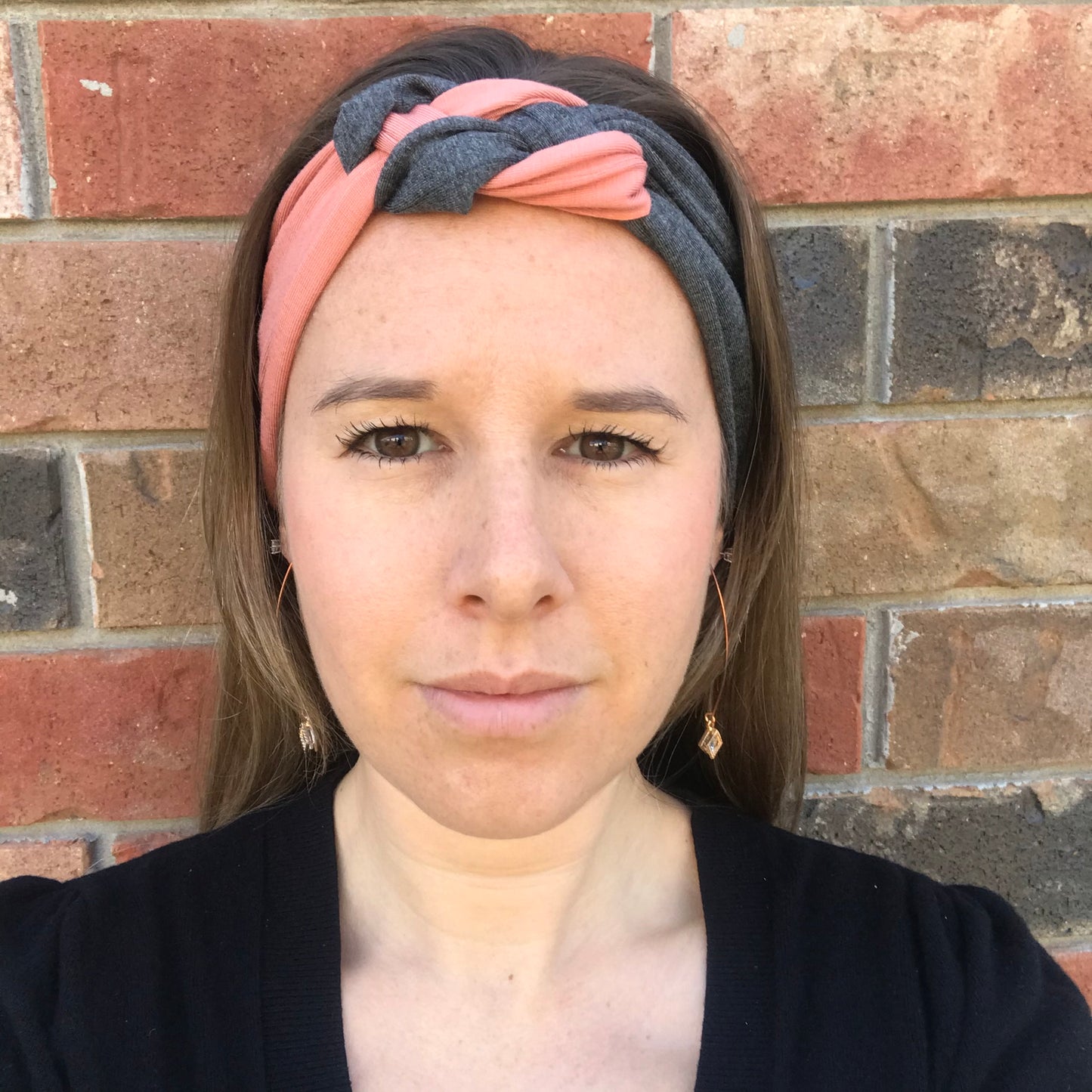Knot headband with dark gray base and pink coral twist at the center