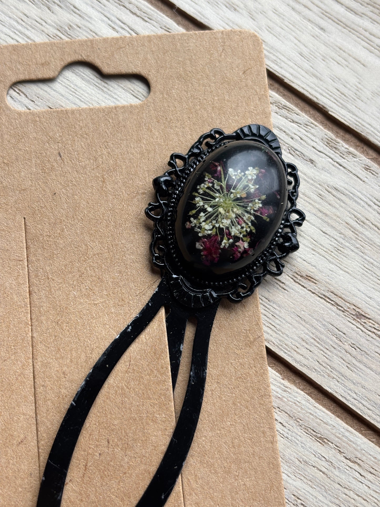 Book marker close-up: black oval cameo floral print on black lace-edged frame