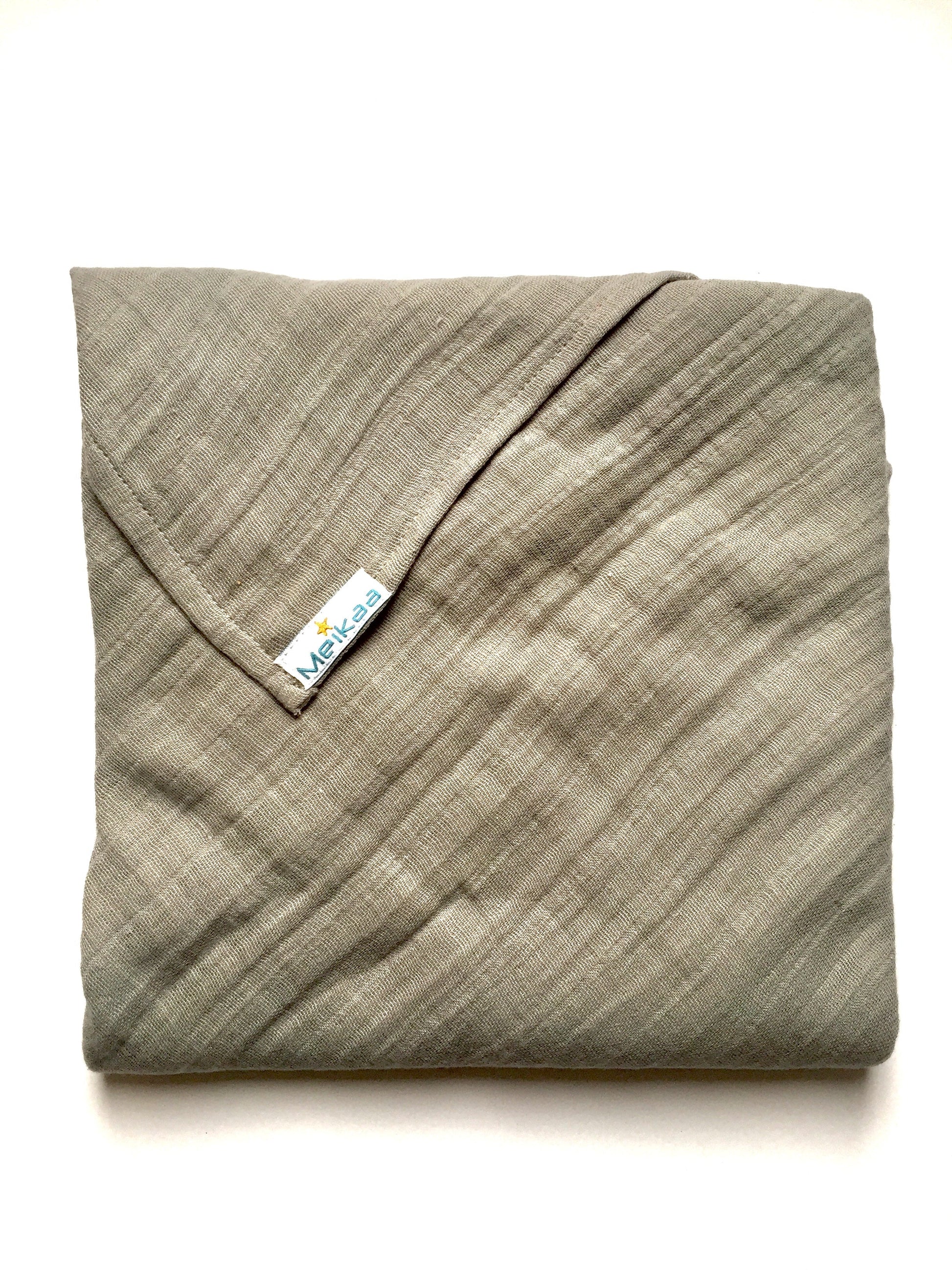 Light gray swaddle blanket with stitched corner and Meikaa tag