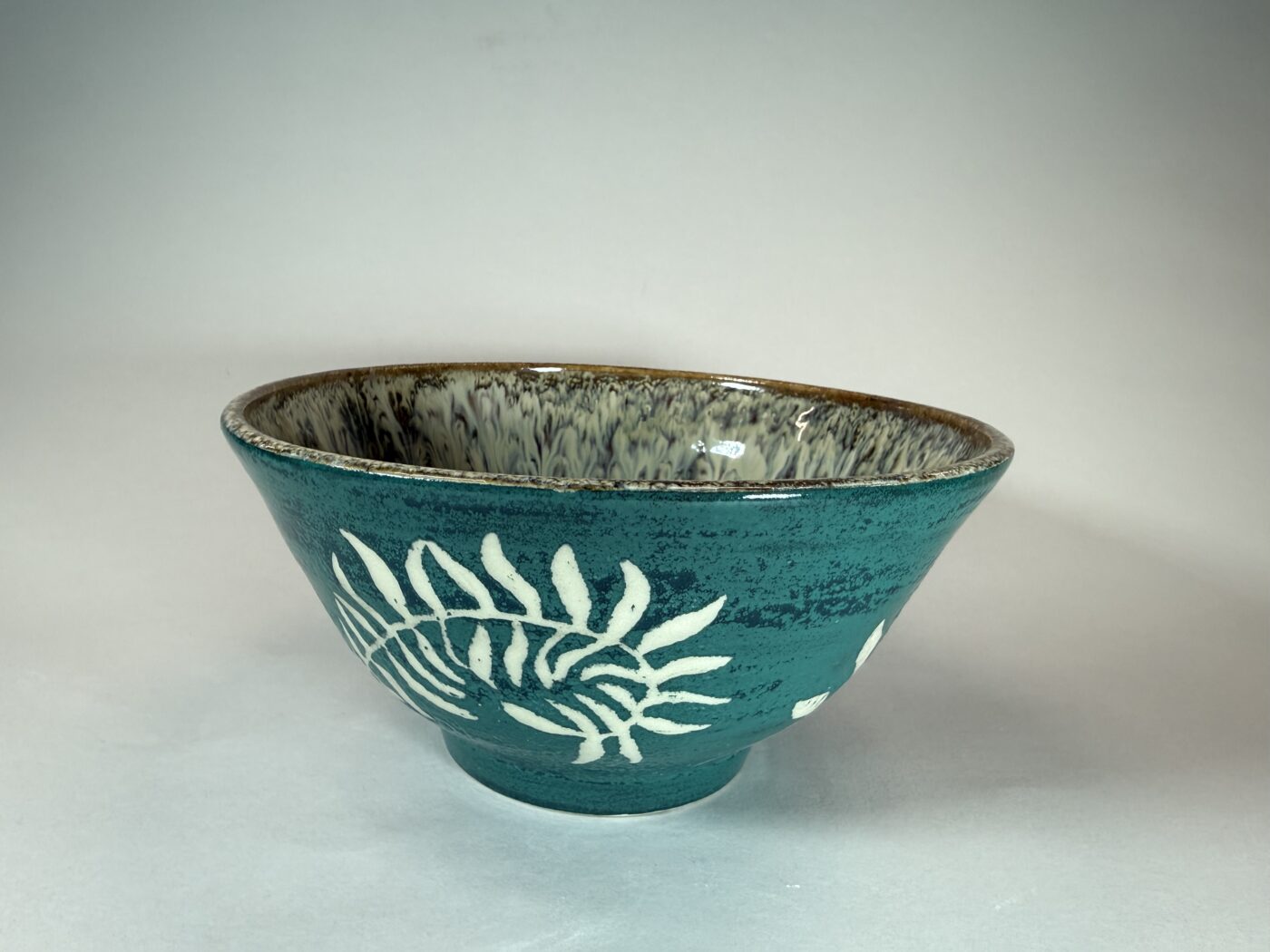 Ceramic bowl in teal with white fern cascade design and brown rim
