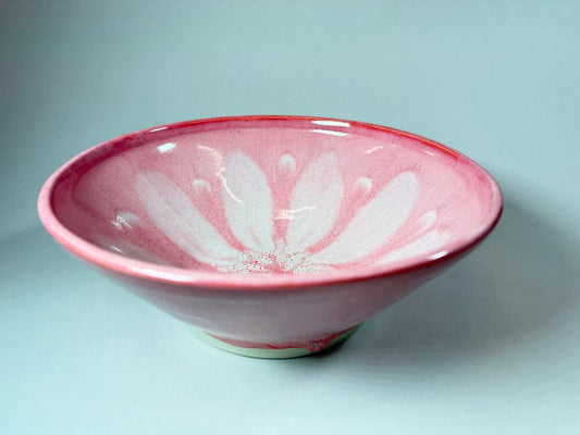 Pink ceramic bowl with white petal-burst pattern, shallow round shape