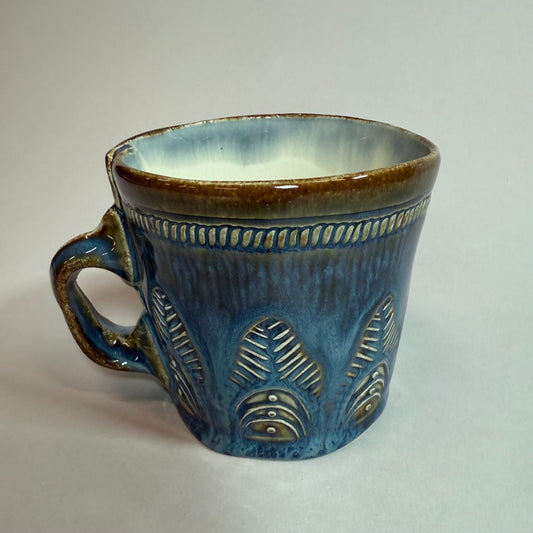 Denim blue ceramic mug with curved handle and embossed geometric accents
