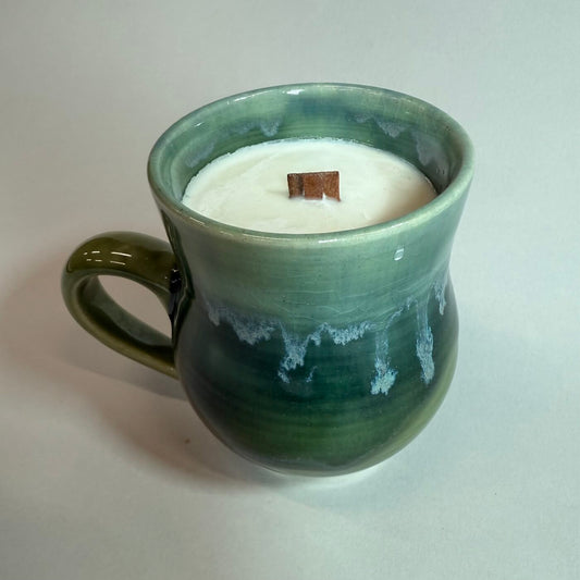 Green ceramic candle mug with side handle, filled with white wax and small center wick.