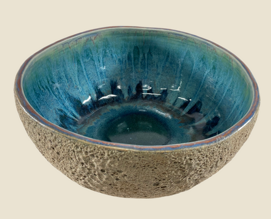 Ceramic bowl with speckled gray exterior and teal blue glossy interior with streaked glaze