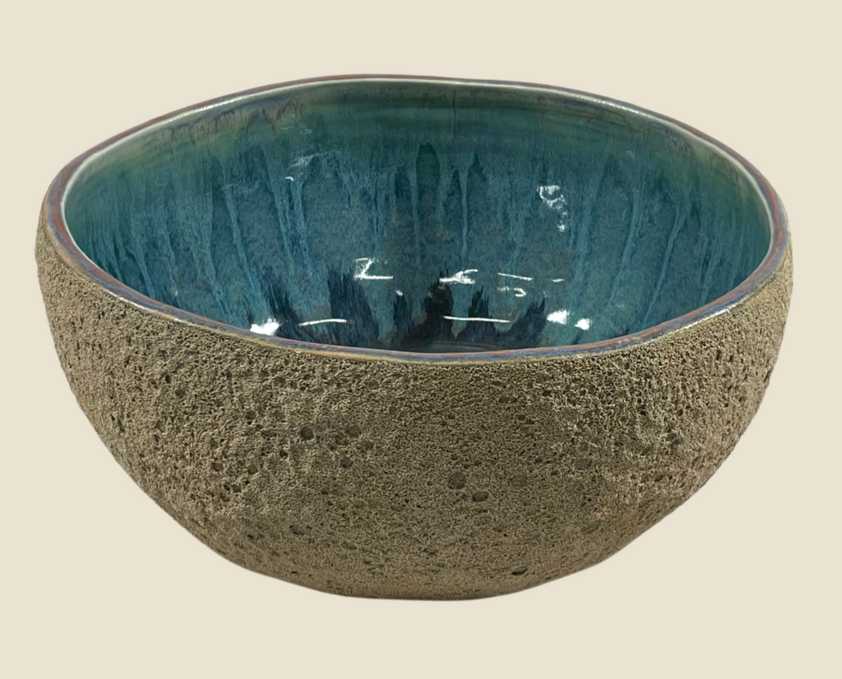 Ceramic bowl, speckled gray exterior, teal interior with glossy streaks and reflective surface
