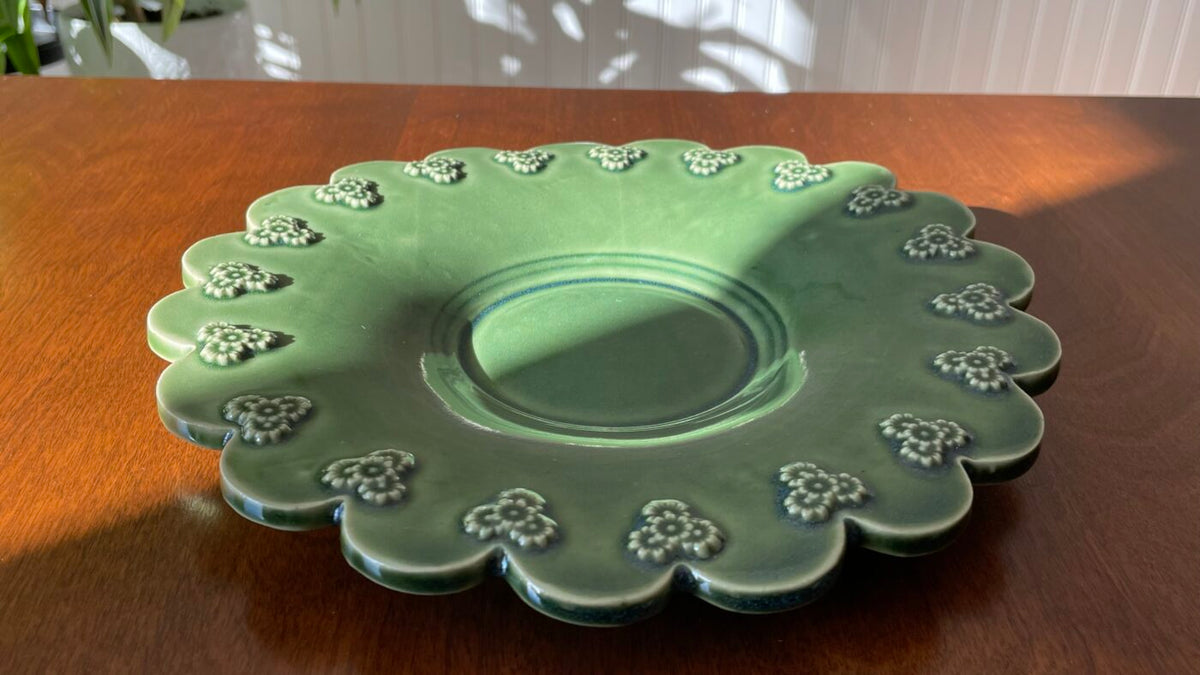 Scalloped light green plate with white flower trim, side view of shallow center