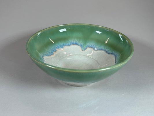 Green ceramic serving bowl with blue wave pattern inside, shallow round shape