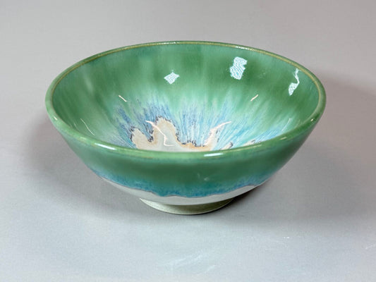 Glazed ceramic serving bowl with green rim and blue interior