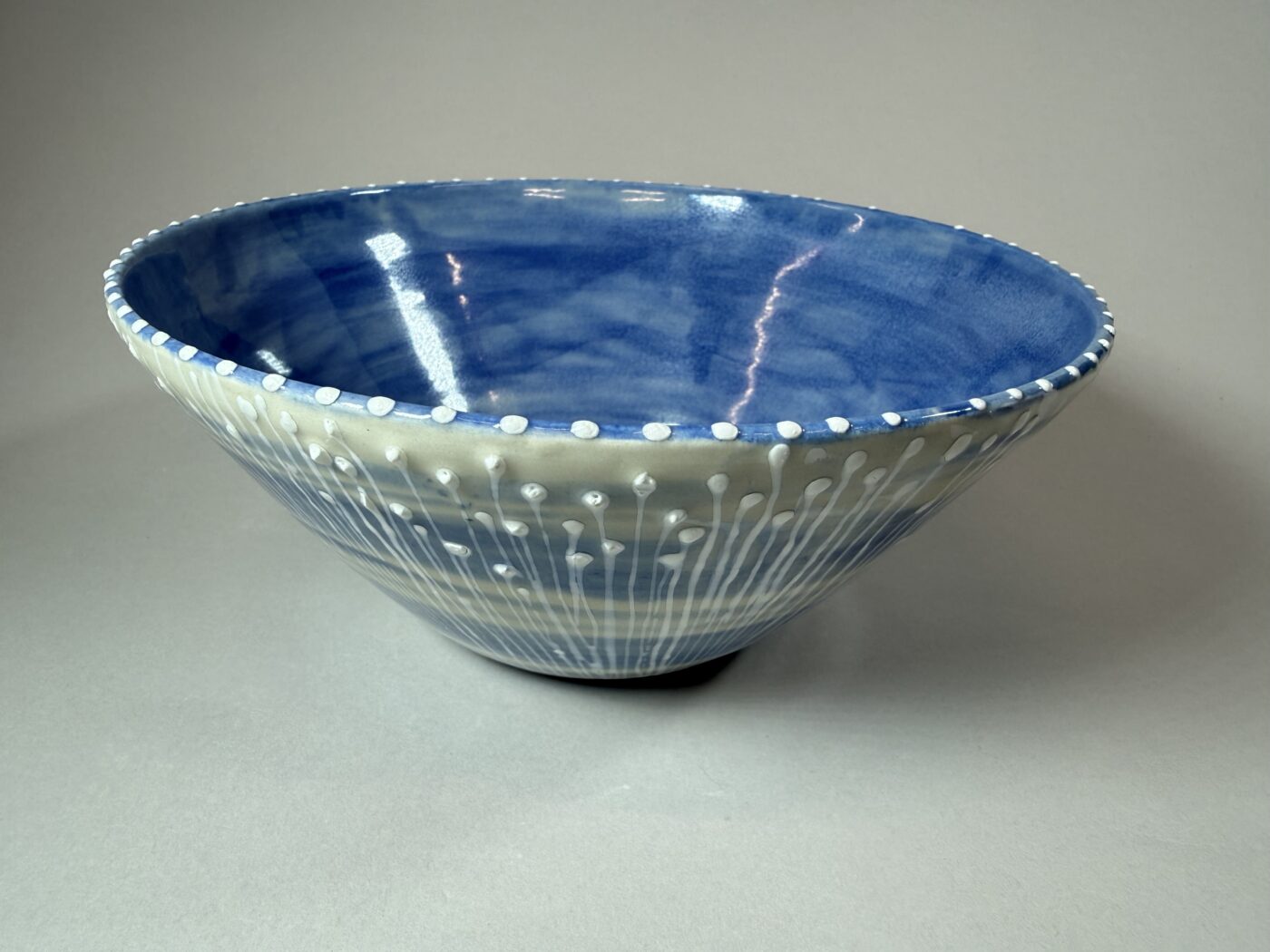 Blue ceramic decorative bowl with white speckled dots and wave pattern