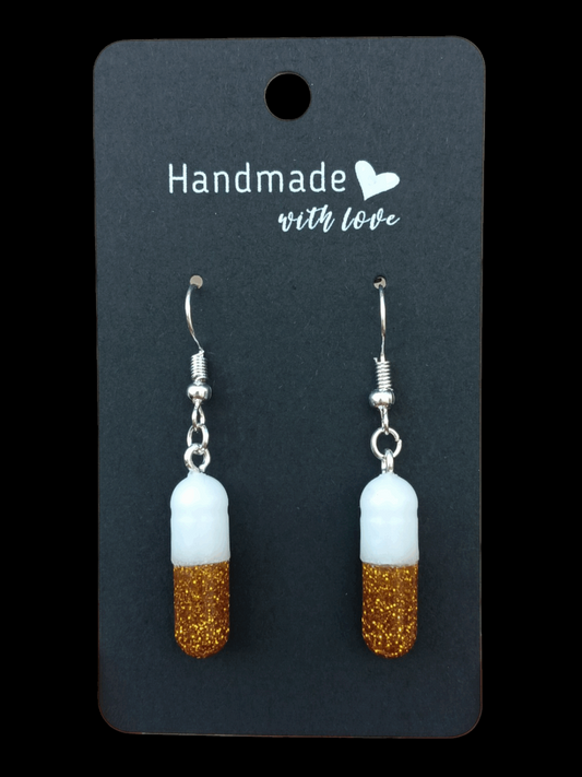 Pill capsule earrings with gold glitter and white beads on silver-tone hooks