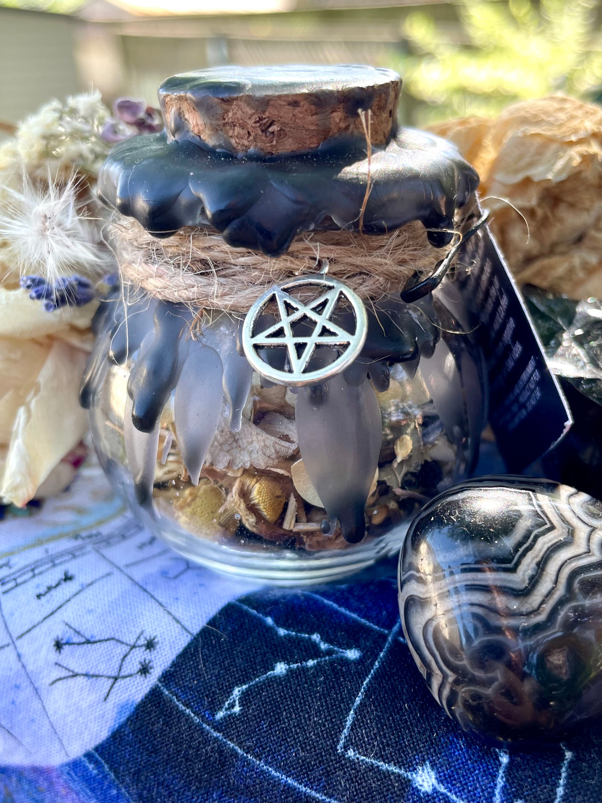 Protection spell jar with dark lid wax and silver pentagram charm on a glass vessel